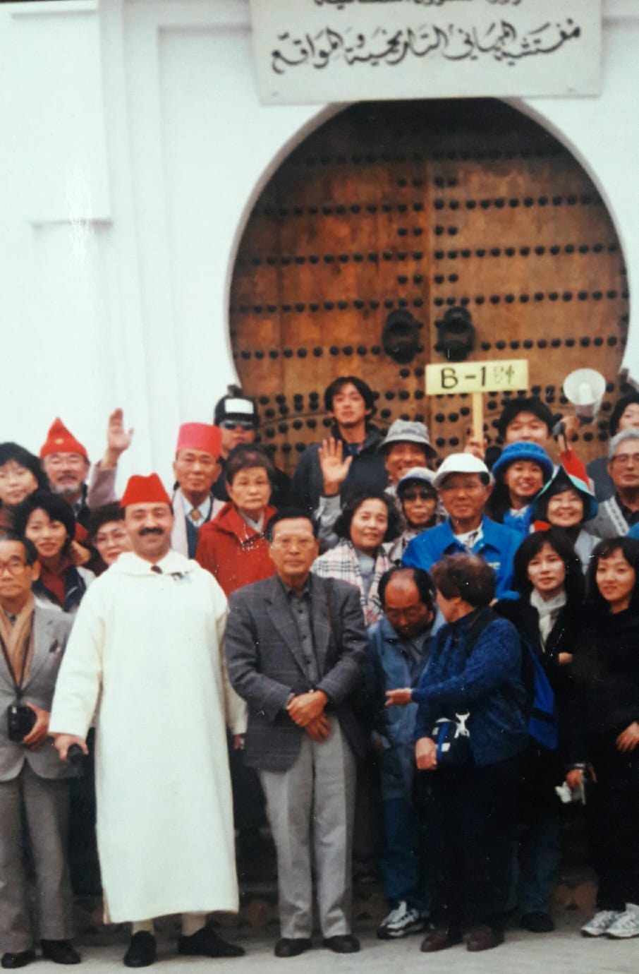 Asian tour group with a guide in traditional Moroccan attire