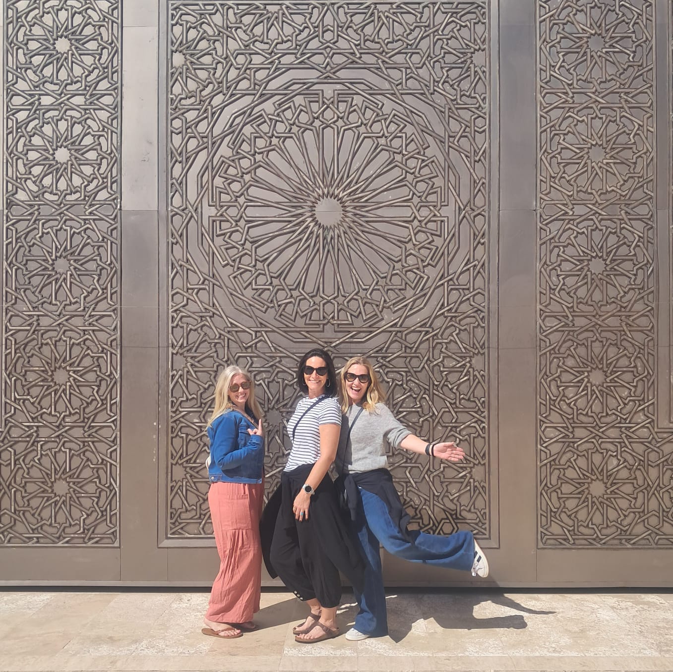 Tourists posing in front of intricate Islamic geometric patterns