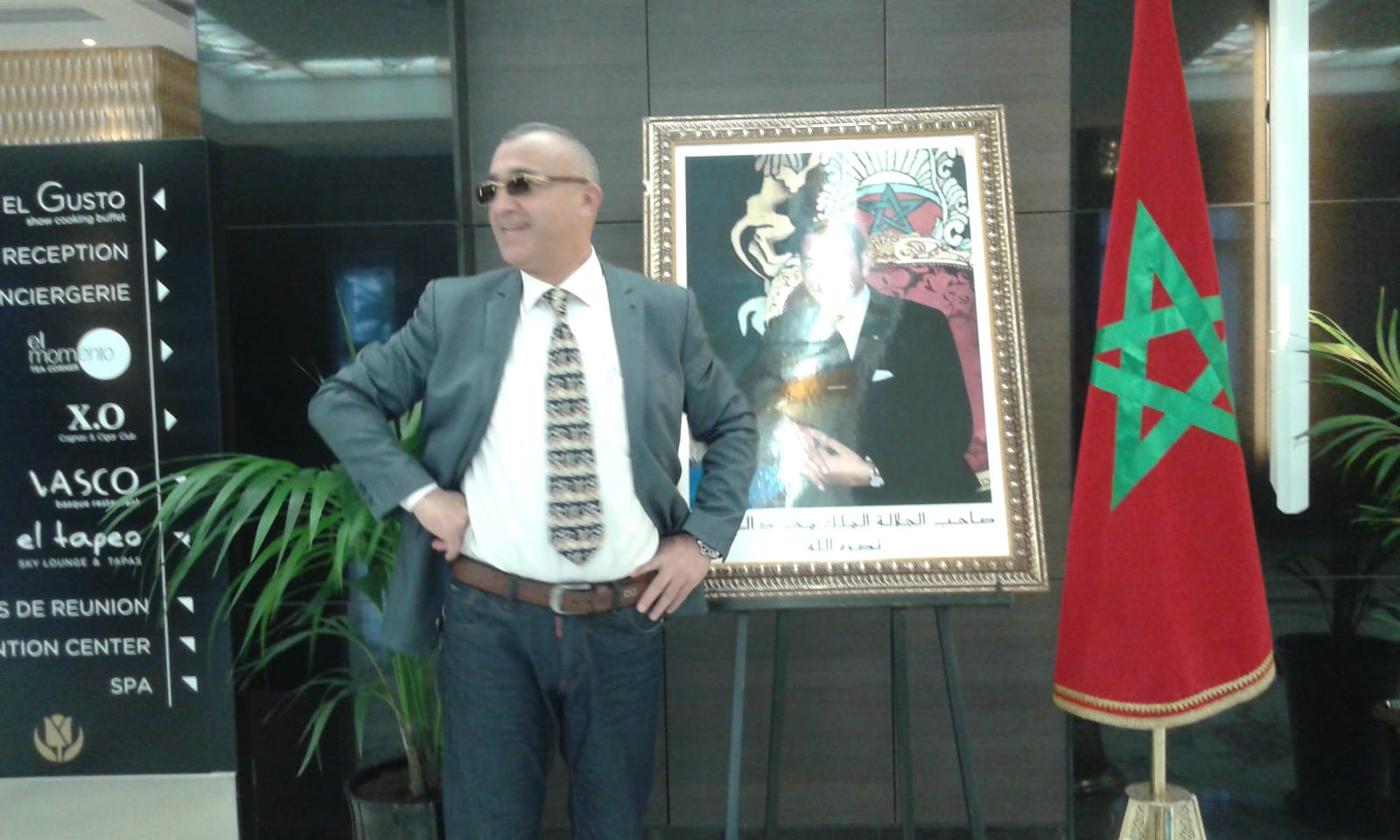 Hamid in professional setting with Moroccan flag