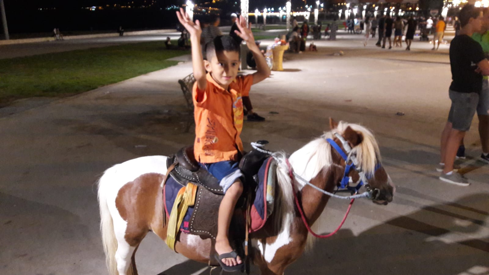 Child enjoying a pony ride along the Tangier promenade at night